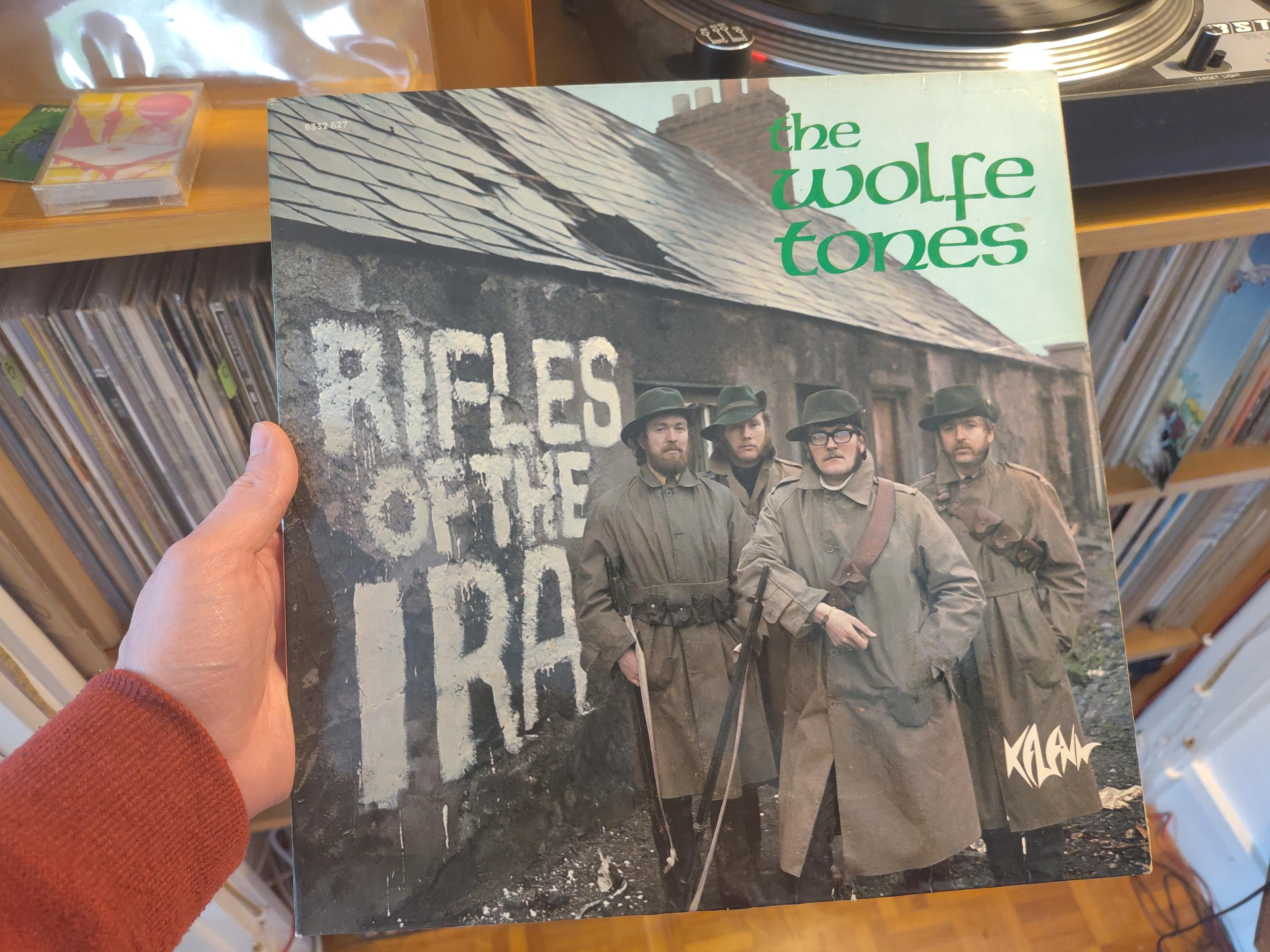 Le groupe, habillé en imperméables, chapeaux sur la tête et fusil à la main, pose devant une chaumière. Sur le mur, peints en blanc a la taille d'un être humain, les caractères du titre de l'album.