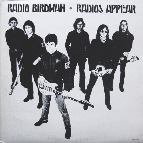 Photo de pochette de disque en noir et blanc : 6 musiciens debouts sur un fonds blancs, trois d'entre eux avec leurs instruments (guitares et basses), les autres sans. Au dessus des musiciens, le nom du groupe et le titre de l'album en lettre pseudo runique