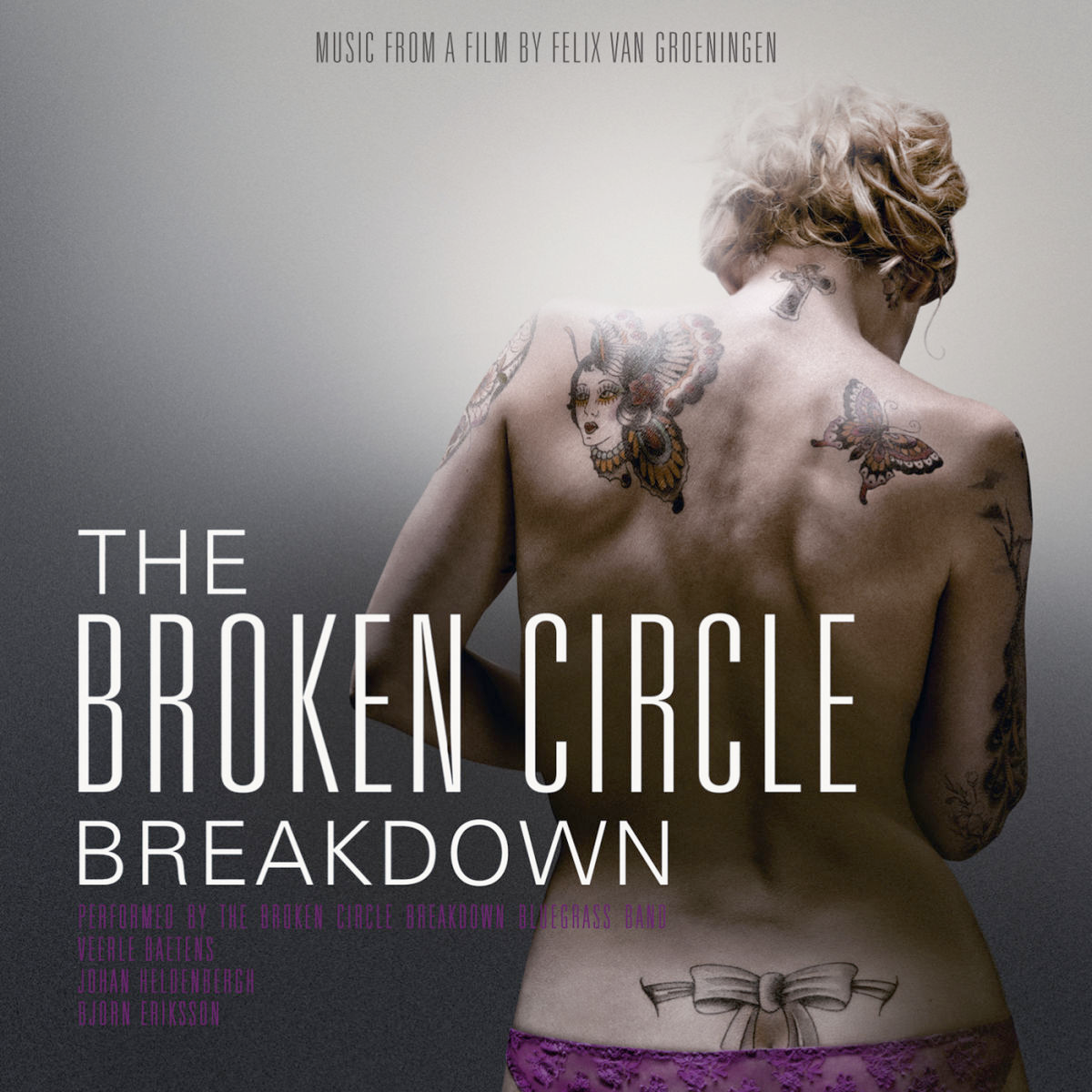 A picture of the back of a white blond women almost naked with purple laced panties and some tattoos. One of them is a butterfly. Colors are pale and the background is just a white and grey gradient.