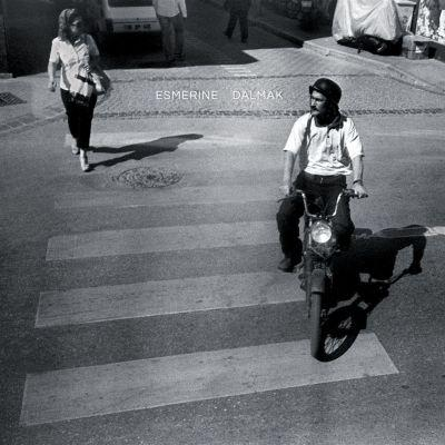 Album cover of Dalmak from the band Esmerine, featuring a man on a motorcycle and a woman crossing the street