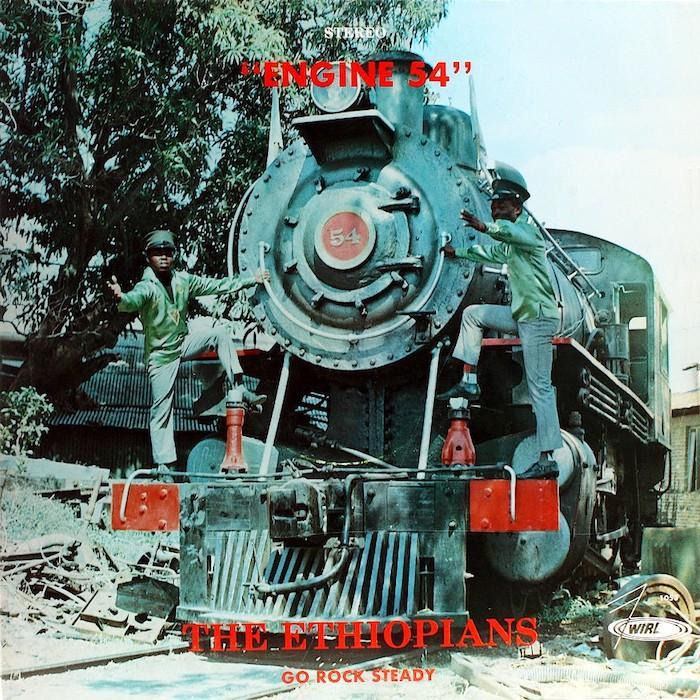 PPochette du vinyl du premier album des Ethiopians, "Engine 54" en lettrages rouges avec la loco verte à la médaille rouge 54 sur les rails au centre allant vers la gauche, les deux musiciens (?) en blue jean, veste et casquettes vertes montés dessus tendant le bras pour aller de l'avant
