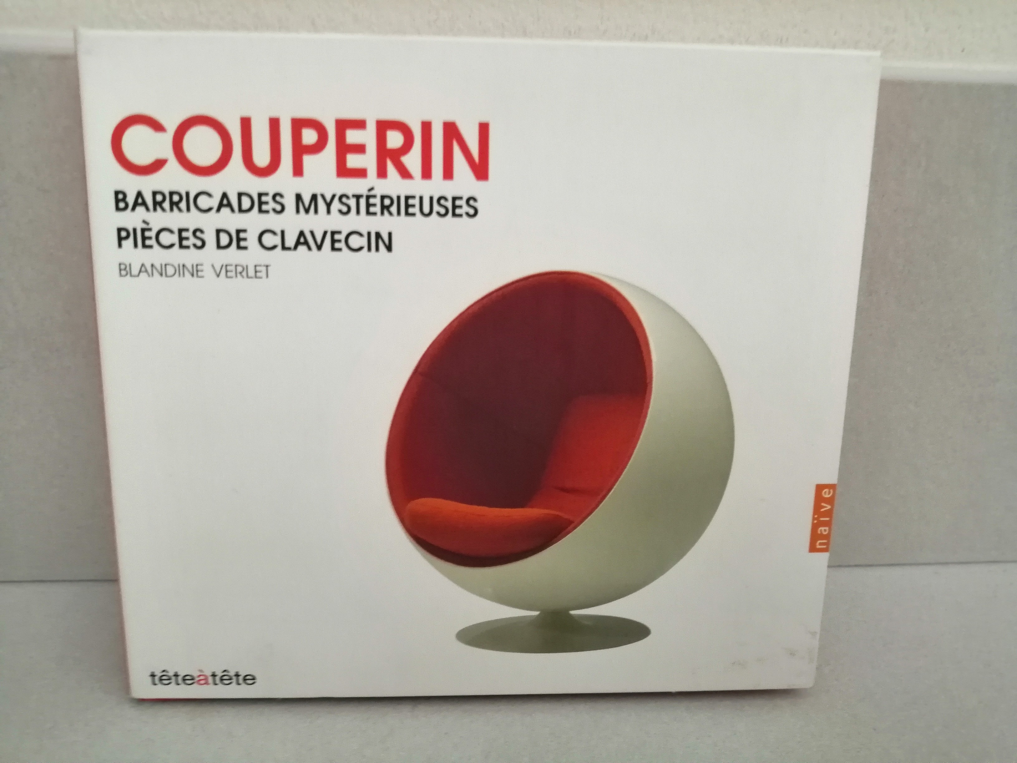Sur un fond blanc, un Ball Chair d'Eero Aarnio blanc avec l'intérieur orange. En haut en grosses lettre orange "COUPERIN".