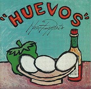 Album dessiné avec un mur turquoise derrière une table marron clair où sont posés un gros poivron vert, une bouteille type tabasco et un plat courbe avec trois oeufs blancs (huevos). Le titre Huevos apparaît en rouge au dessus de la nature morte, le nom du groupe Meat Puppets en noir en lettrages fins noirs juste en-dessous