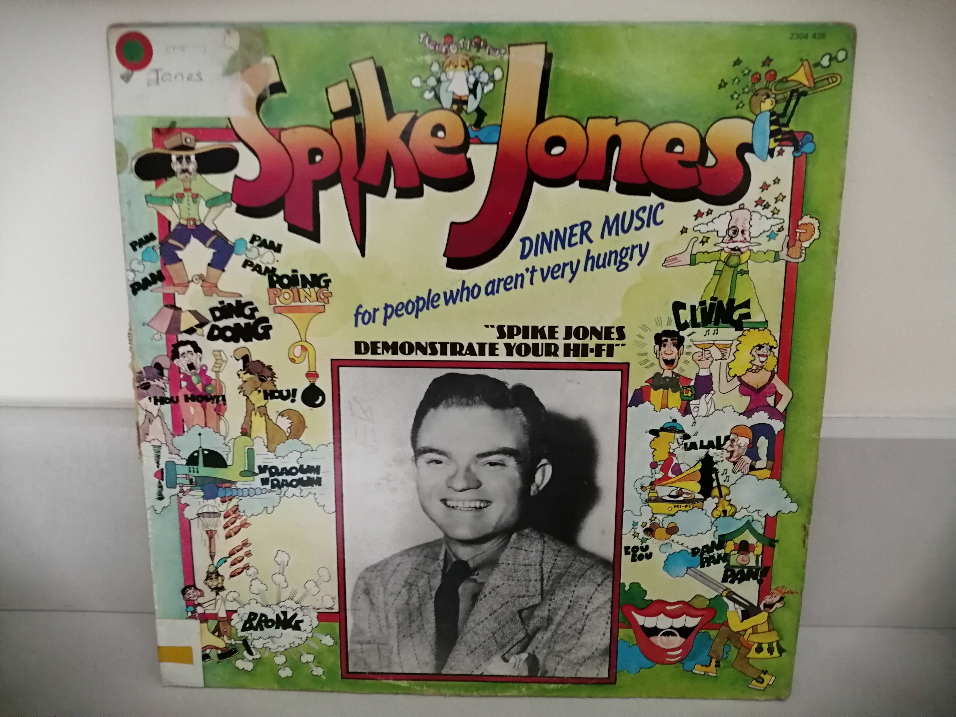 Des personnages dessinés en couleur avec des onomatopées illustrant les bruitages présent sur l'album (Ding, Boing, Cling...) entournent une photo noir et blanc de Spike Jones souriant.