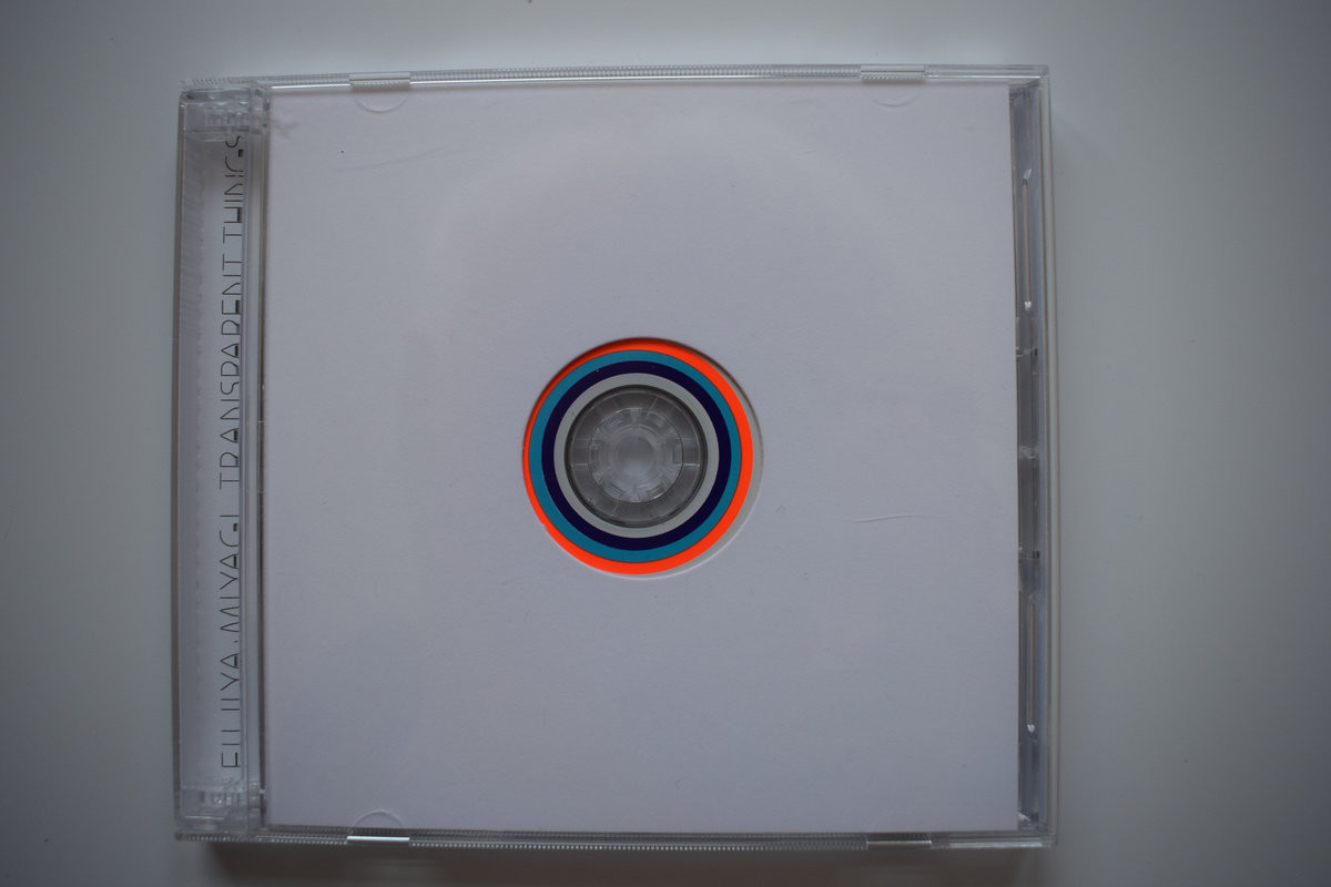 A CD album. The inner cover is all white with just a round hole that allows you to see the surface of the CD, displaying 3 colored circles (navy blue, sky blue and orange).