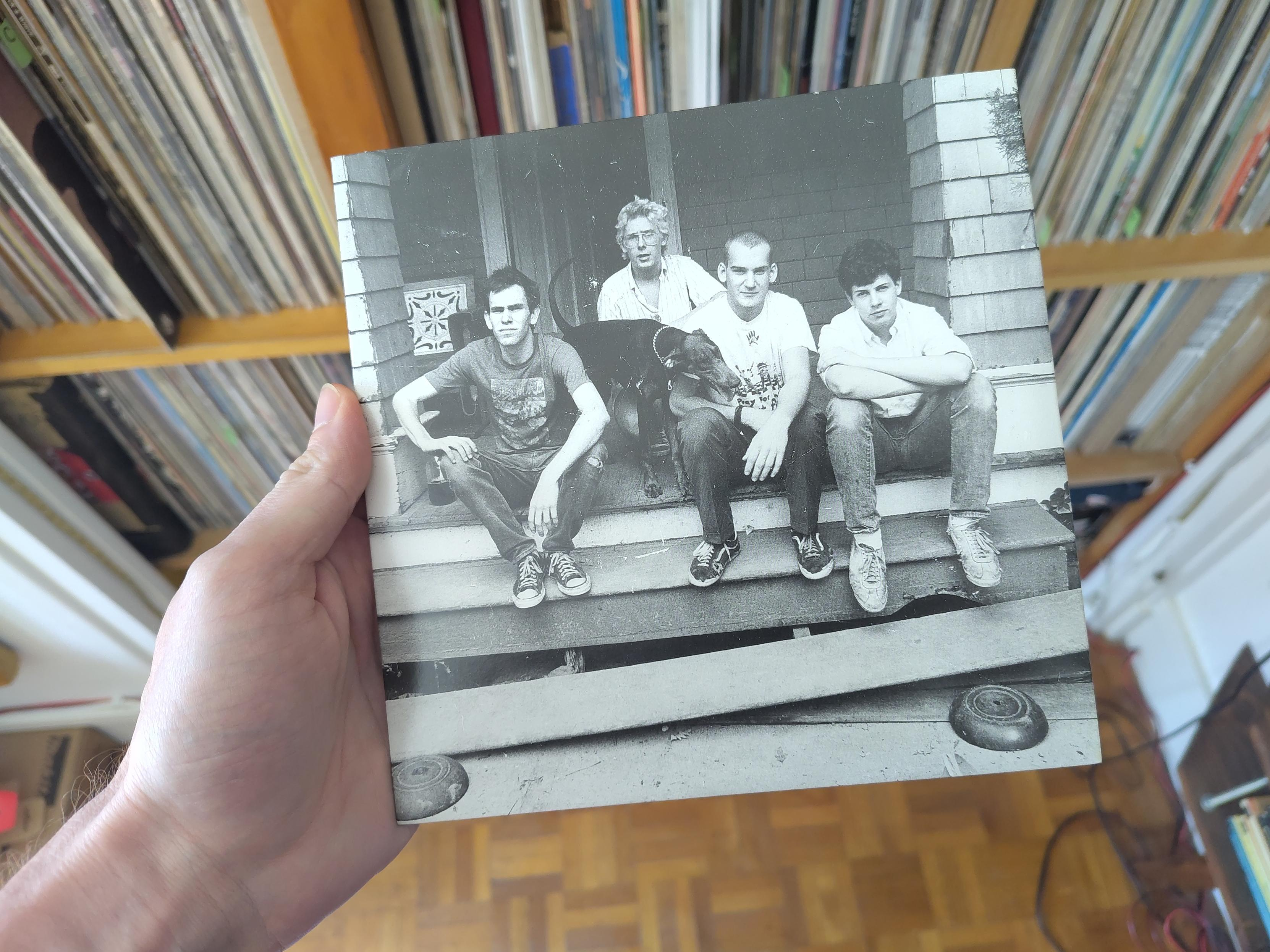 Les quatre membres du groupe, assis sur le perron d'une maison, photo issue d'une session parmi laquelle une autre photo a été retenue et diffusée plus massivement plus tard. Ils sont tous très jeunes et ne donnent pas particulièrement l'impression d'être punks. Un chien qui à l'air sympa est au milieu d'eux.