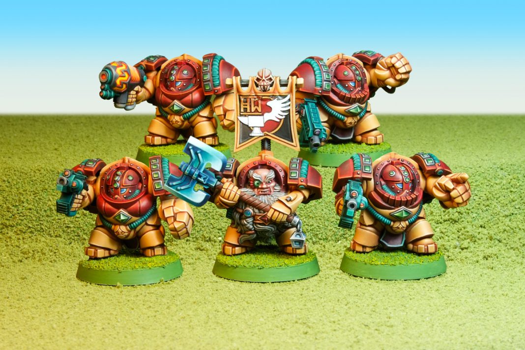 Une escouade de cinq figurine de nains de Fantasy en version SF "Space Marines" : ils sont équipés de grosses armures énergétiques. Ils ont des proportions très exagérées avec des grosses mains et des grosse têtes, et sont peints en orange et jaune vifs, sur des bases vert vifs